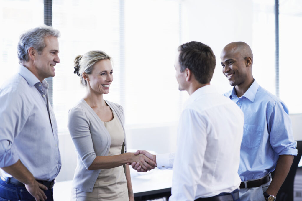 Shot of a diverse group of coworkers shaking hands and talking in an office